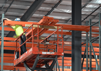 Skyjack equipment example showing employee on heightened scissor lift leaning over to drill something