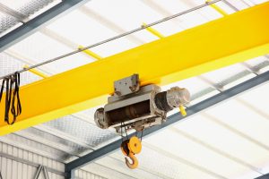 Overhead crane beam used for lifting heavy materials in a warehouse setting, part of a complete overhead cranes system.
