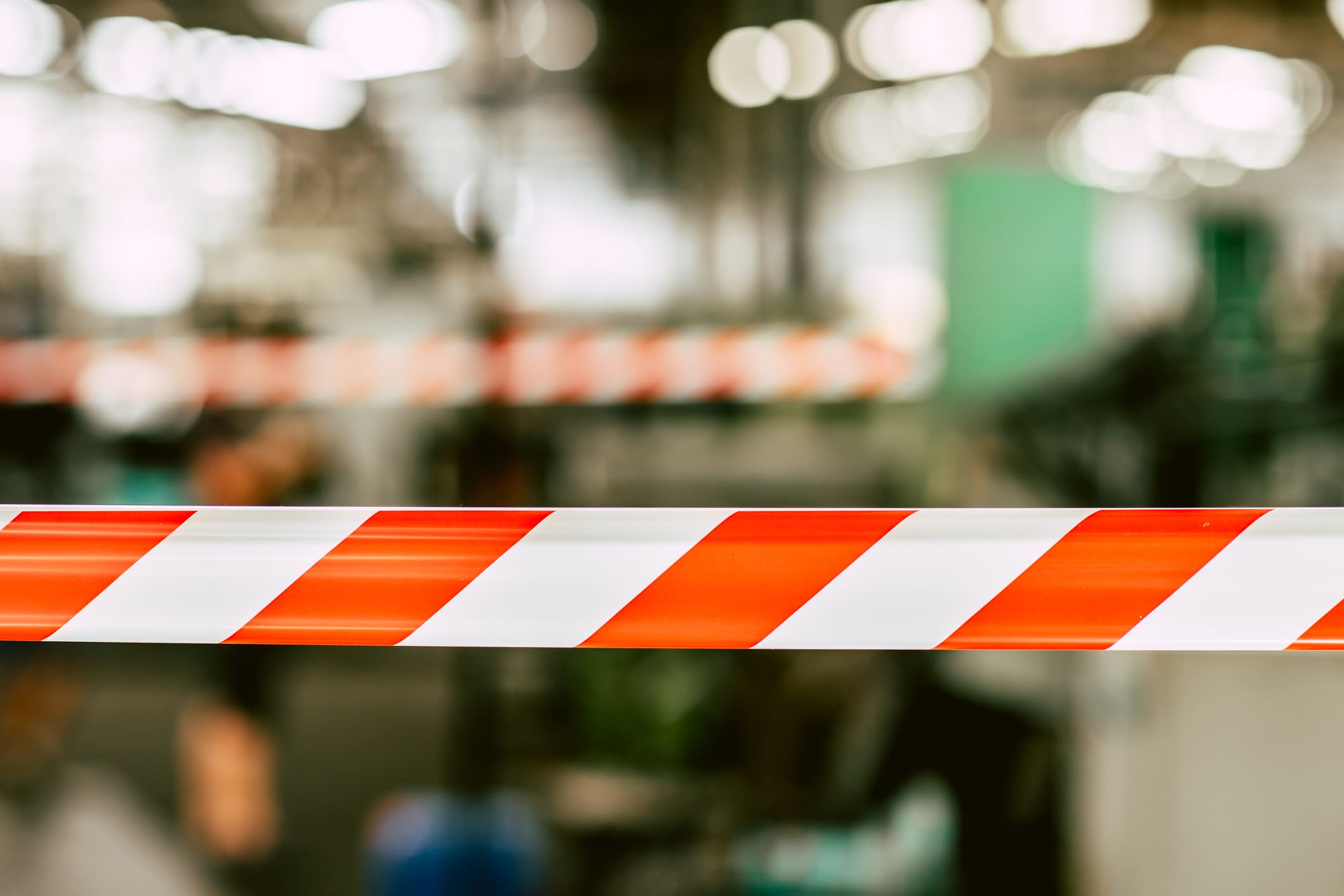 Incident investigation for MA facility. Image shows orange and white safety tape with blurred industrial warehouse background.