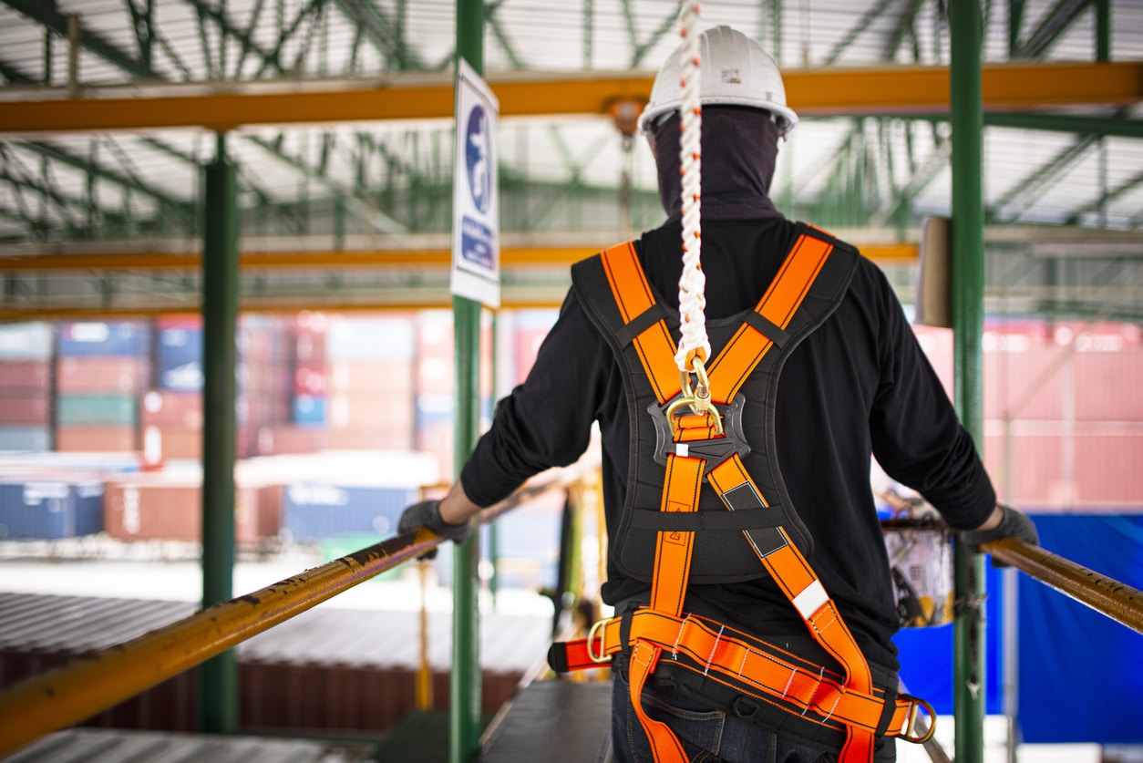 Construction worker's wearing personal protection equipment (PPE) while walking atop a catwalk, demonstrating proper fall protection measures taught in Maybury's fall protection training course in MA & CT.